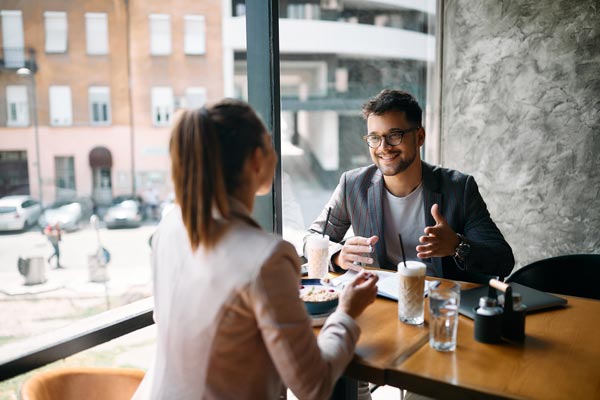 business man communicating with female colleague over breakfast