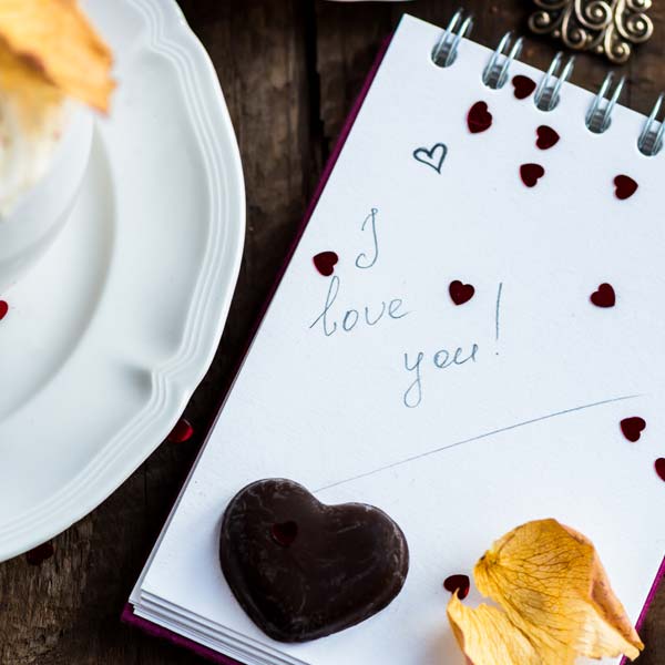 cappuccino with a note saying i love you and heart shaped chocolate with confetti shaped hearts