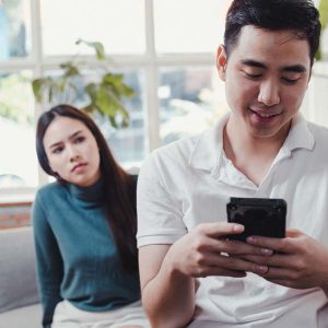 How to Forgive a Cheating Husband or Cheating Wife woman looking over husbands shoulder while he is texting on his phone
