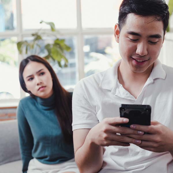 How to Forgive a Cheating Husband or Cheating Wife woman looking over husbands shoulder while he is texting on his phone
