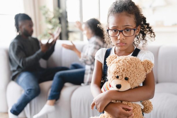 sad girl feeling scared while her parents discuss divorce